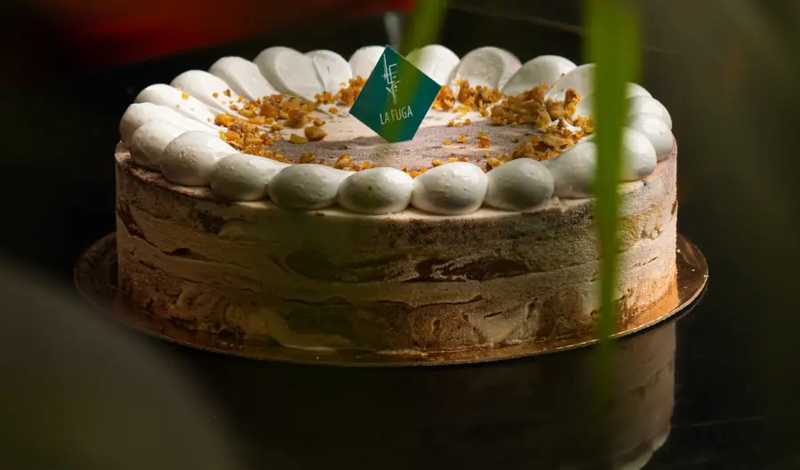 Dolce Biscotto : tarte glacée aux éclats caramélisés, pastilles de chantilly, sur table laquée noire