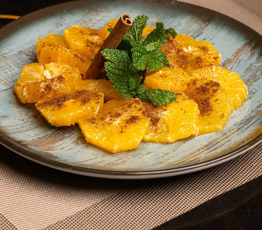 Orange à la cannelle : tranches d'orange à la cannelle, menthe fraîche et bâton de cannelle, assiette céladon