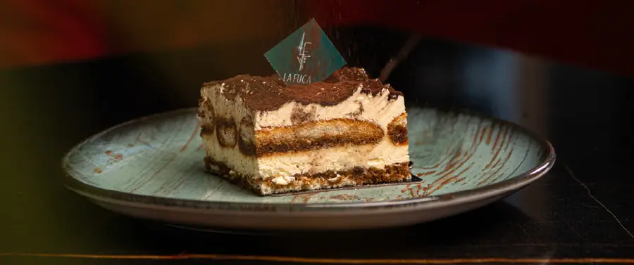 Part de tiramisu au losange céladon, cacao saupoudré au moment, sur assiette céladon