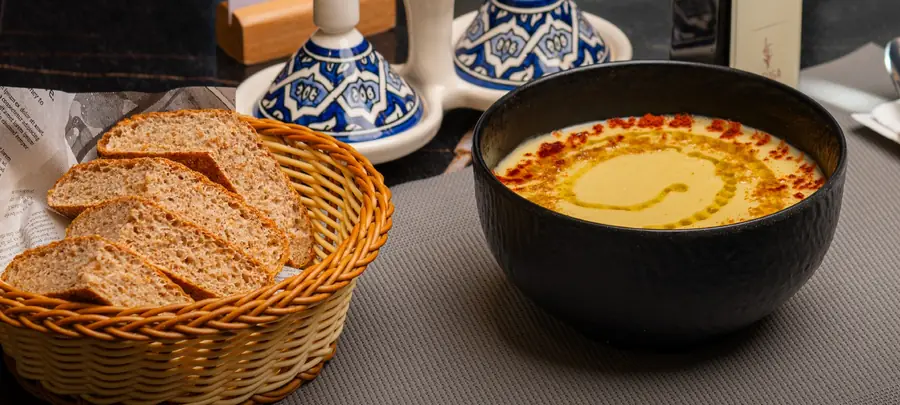Velouté à l'huile d'olive et paprika, panier de pain, salière et poivrier en petits tajines bleus, cuir rouge capitonné derrière