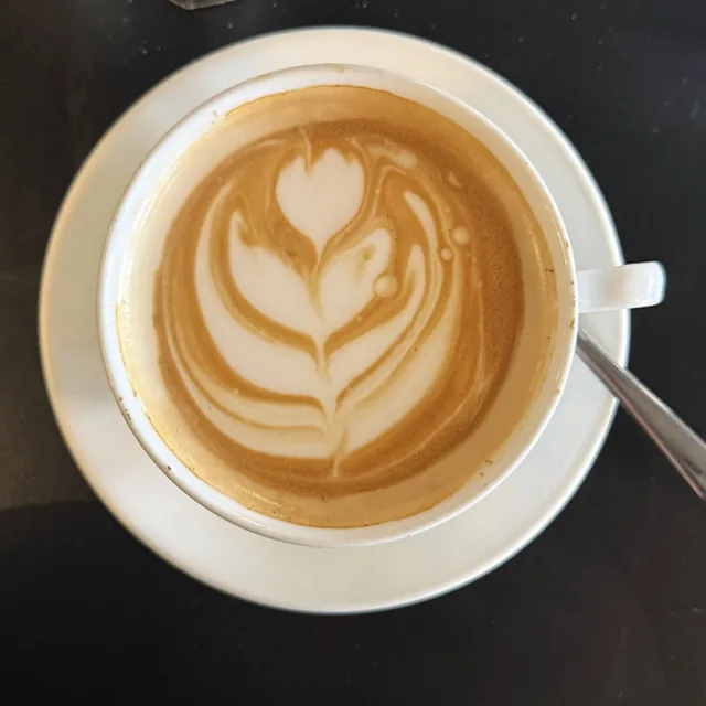 Cappuccino à la rosette de mousse de lait, vu de haut, sur la table laquée noire
